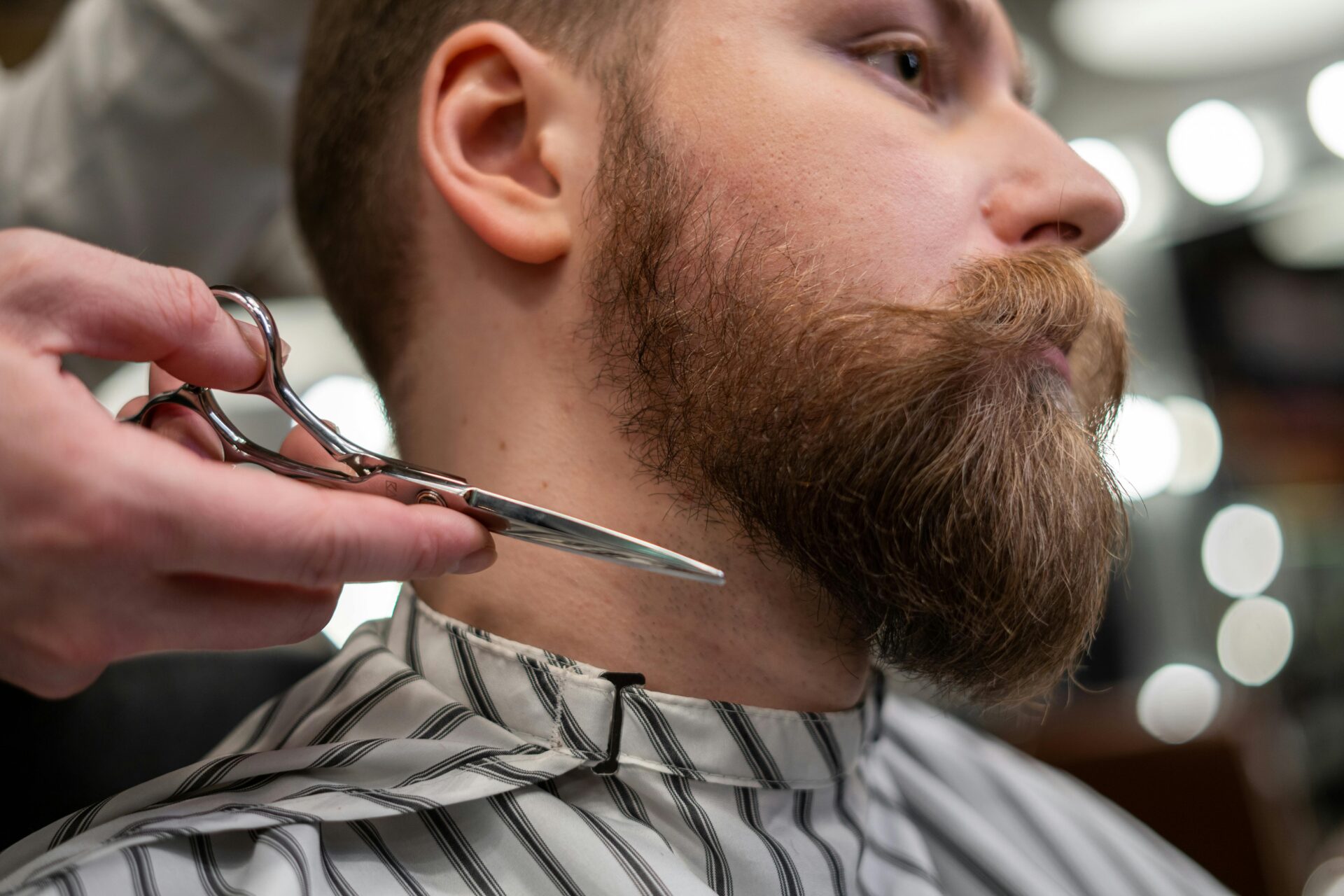 A man getting his beard trimmed by a barber