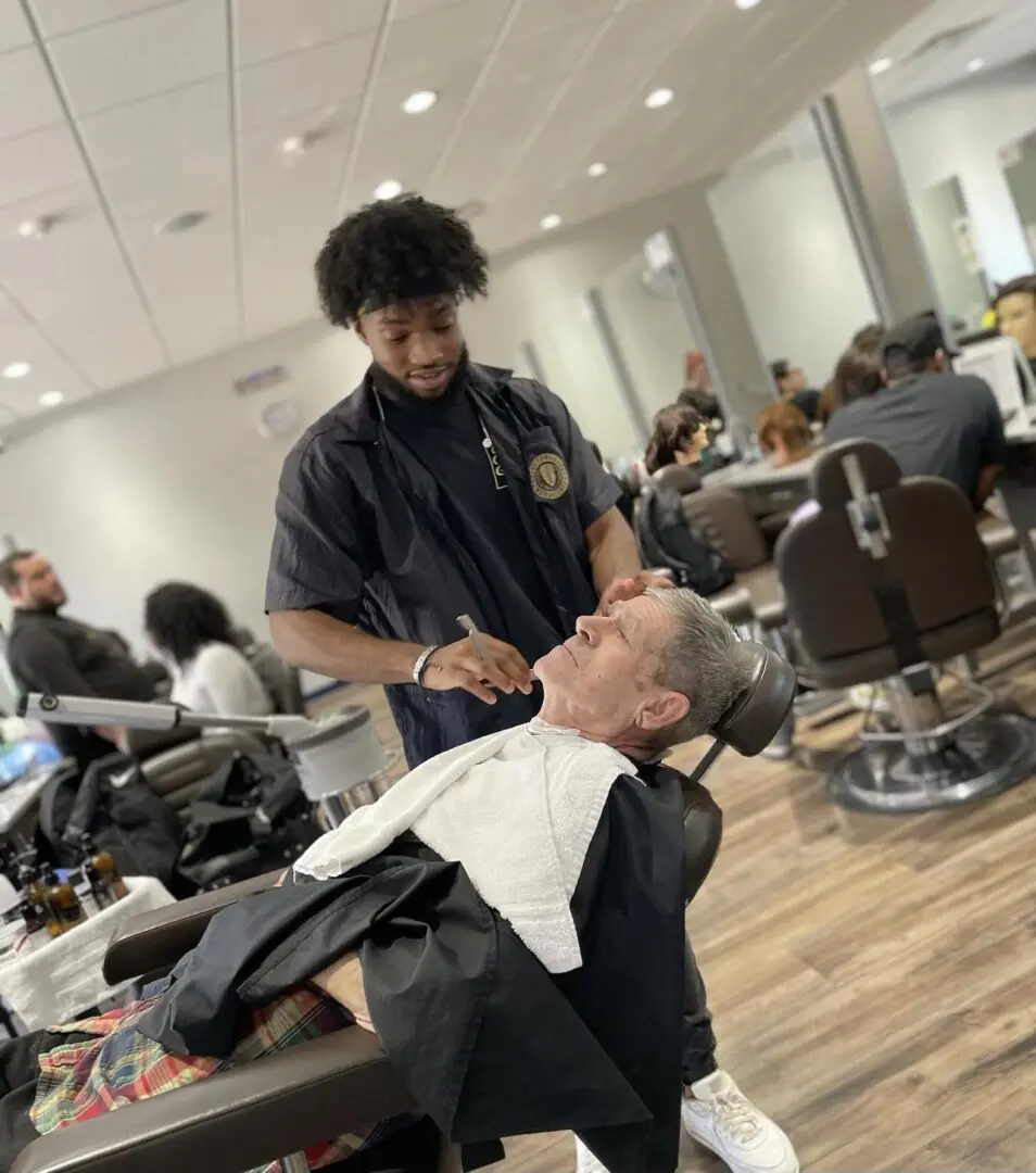 A barber cutting another man 's hair in an office.