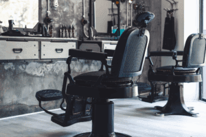 A row of empty barber chairs and styling stations in a barbershop.