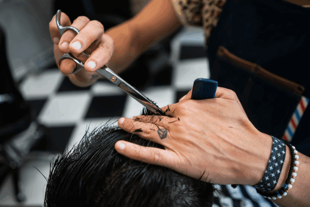 Close-up of barber’s hands cutting male client’s hair.