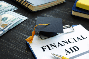 Graduation cap with cash and “FINANCIAL AID” document on table.